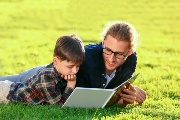 Father and his little son reading book outdoors — 스톡 사진