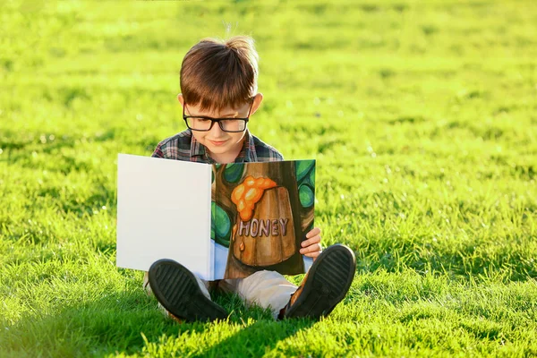 Cute little boy reading book outdoors — Stock Photo, Image