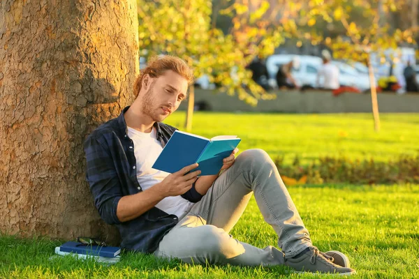 Knappe man die buiten een boek leest — Stockfoto