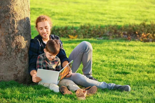 Father and his little son reading book outdoors — 스톡 사진