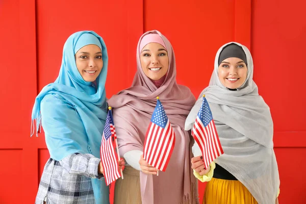 Junge muslimische Frauen mit US-Flaggen auf farbigem Hintergrund — Stockfoto