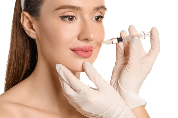 Young woman receiving filler injection against white background — 스톡 사진