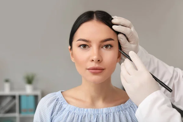 Plastischer Chirurg trägt in Klinik Spuren im Gesicht des Patienten auf — Stockfoto