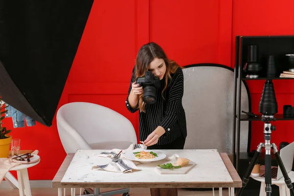 Young woman taking picture of pasta in professional studio