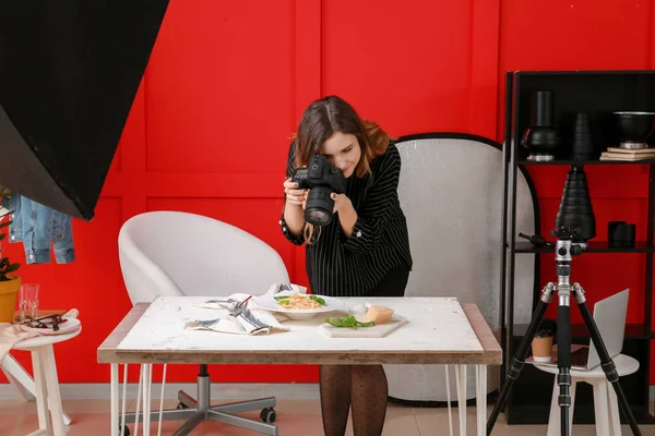 Young woman taking picture of pasta in professional studio