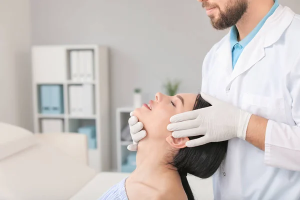 Plastisch chirurg onderzoeken jonge vrouw gezicht voorafgaand aan operatie in kliniek — Stockfoto