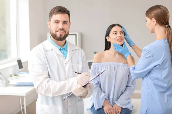 Mannelijke plastisch chirurg met assistent en patiënt in kliniek — Stockfoto