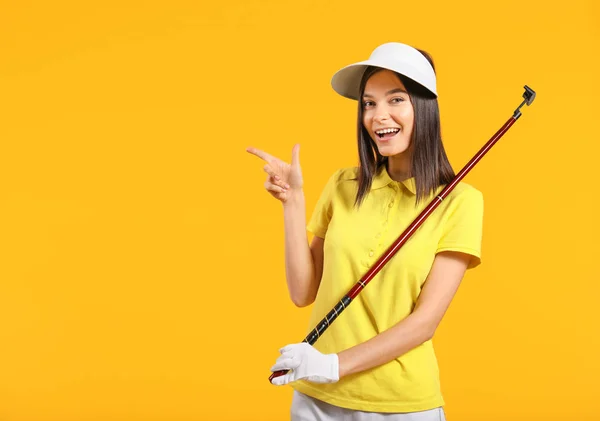 Beautiful female golfer pointing at something on color background — 스톡 사진