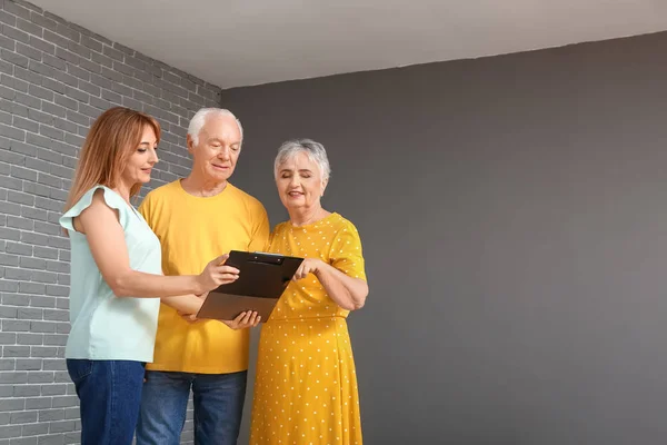 Agente inmobiliario femenino trabajando con pareja de personas mayores en interiores —  Fotos de Stock
