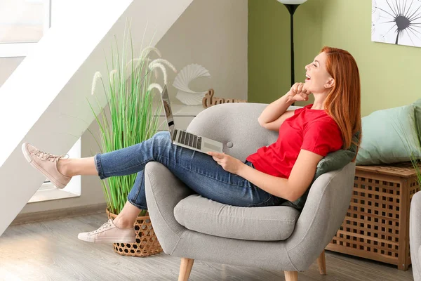Bella donna con computer portatile seduto in poltrona a casa — Foto Stock