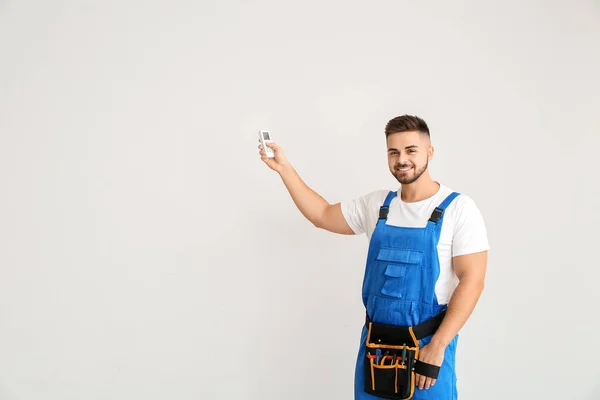 Técnico masculino com ar condicionado controle remoto no fundo de luz — Fotografia de Stock