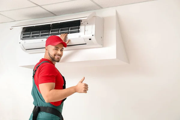 Técnico masculino reparando ar ar condicionado dentro de casa — Fotografia de Stock