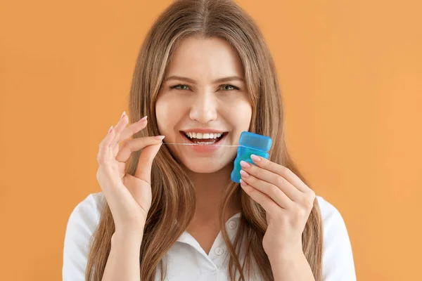 Beautiful young woman with dental floss on color background — Stock Photo, Image