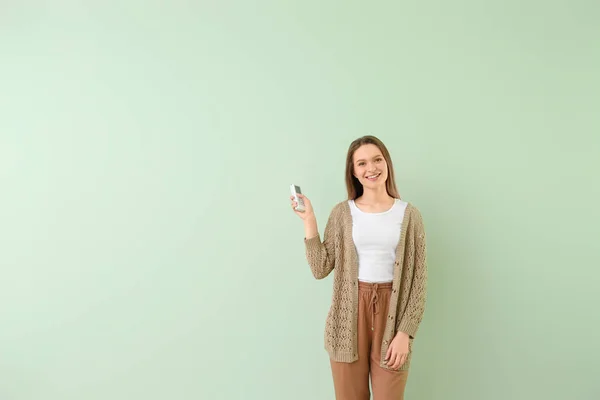 Ung kvinna med luftkonditionering fjärrkontroll på färg bakgrund — Stockfoto