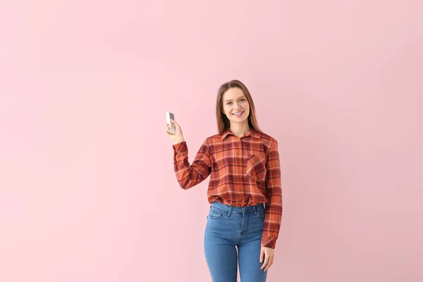 Jeune femme avec climatiseur télécommande sur fond de couleur — Photo