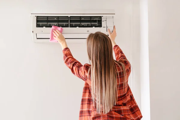 Jonge vrouw reinigen airconditioner thuis — Stockfoto
