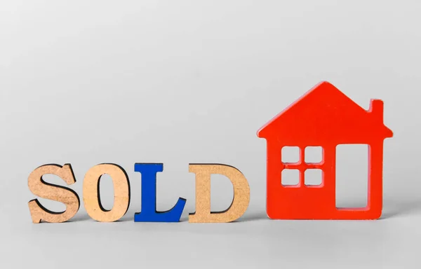 Wort verkauft mit Figur des Hauses auf weißem Hintergrund. Konzept des Immobilienerwerbs — Stockfoto