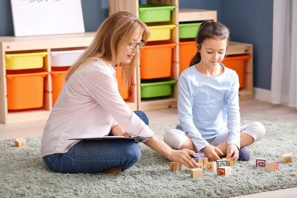 Психолог работает с маленькой девочкой в помещении — стоковое фото