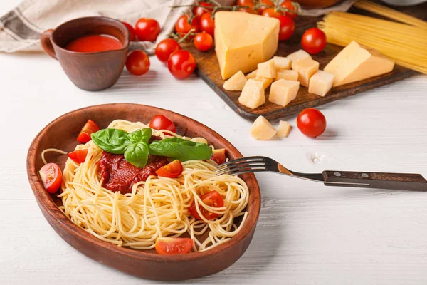 Talerz z smacznym makaronem i sosem pomidorowym na białym stole — Zdjęcie stockowe