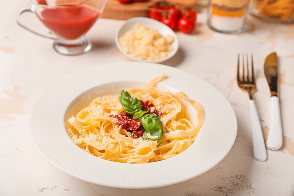 Тарелка с вкусной пастой и томатным соусом на белом столе
