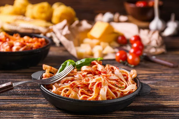 Frying pan with tasty pasta and tomato sauce on table — Stock Photo, Image