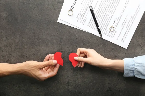 Hands of couple with broken heart on dark background. Concept of divorce