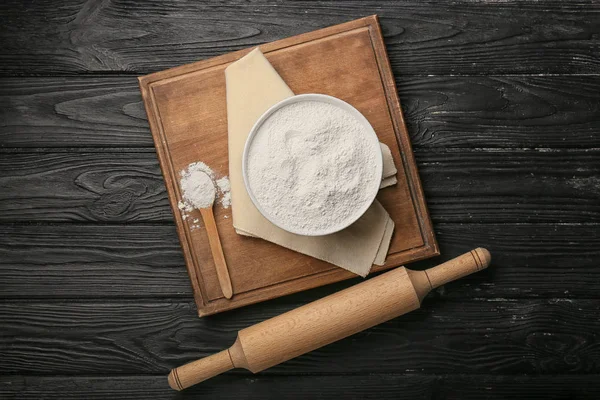 Flour with rolling pin and board on dark wooden background — Stock Photo, Image