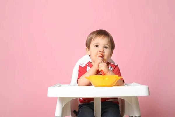 Lindo niño comiendo sabroso alimento para bebés contra el fondo de color — Foto de Stock