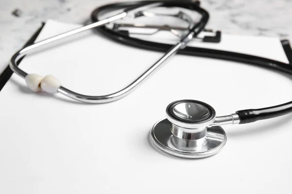 Stethoscope and clipboard on table, closeup — ストック写真