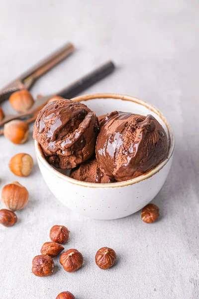 Chutná zmrzlina v misce a ořechy na šedém pozadí — Stock fotografie