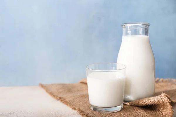 Glas und Flasche leckere Milch auf weißem Tisch — Stockfoto