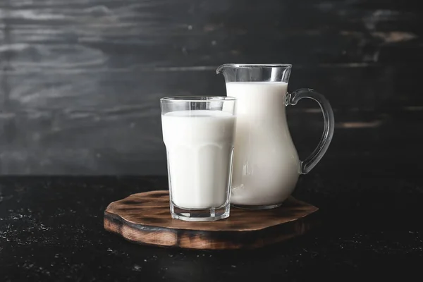Glass and jug of tasty milk on dark table — Stock Photo, Image