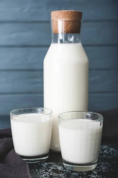 Glasses and bottle of tasty milk on dark table — Stock Photo, Image