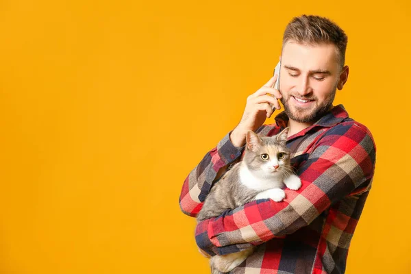 Uomo con gatto carino che parla per telefono su sfondo a colori — Foto Stock