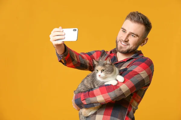 Uomo prendendo selfie con simpatico gatto su sfondo di colore — Foto Stock