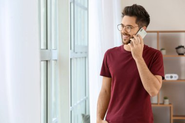 Evde cep telefonuyla konuşan mutlu genç adam.