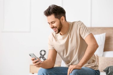 Evde cep telefonu olan mutlu bir genç adam.
