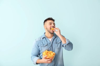 Renkli arkaplanda patates cipsi olan yakışıklı bir genç.