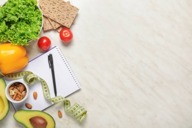 Different healthy food with measuring tape and notebook on light background. Diet concept