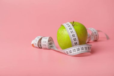 Apple and measuring tape on color background. Diet concept