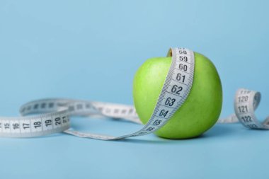 Apple and measuring tape on color background. Diet concept