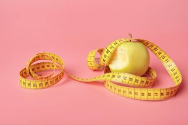 Bitten apple and measuring tape on color background. Diet concept