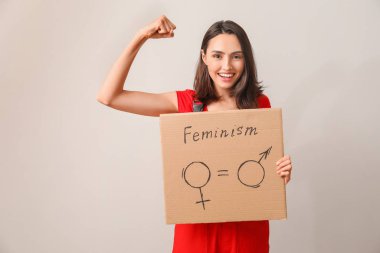 Female worker holding cardboard with symbols of man and woman on light background. Concept of feminism