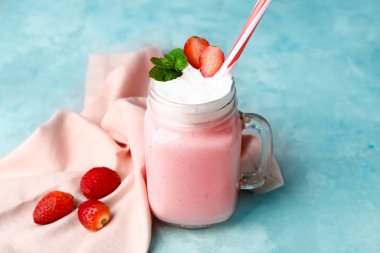 Mason jar of tasty milkshake on color background