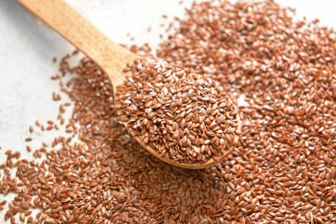 Beyaz arkaplanda kaşık ve keten tohumları