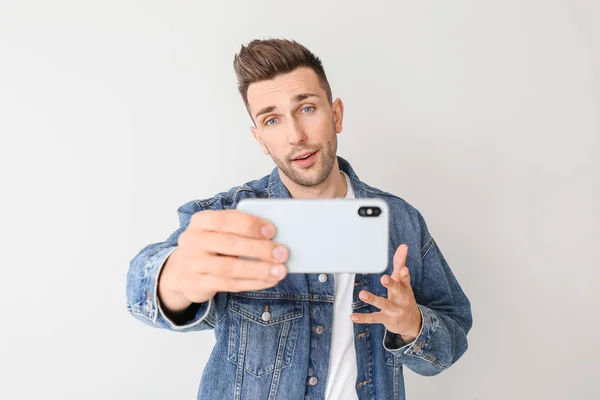 Bonito homem tomando selfie no fundo claro — Fotografia de Stock