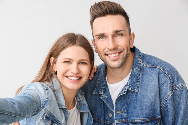 Young couple taking selfie on light background