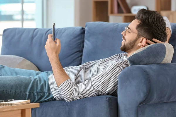 Happy young man with mobile phone at home — 스톡 사진