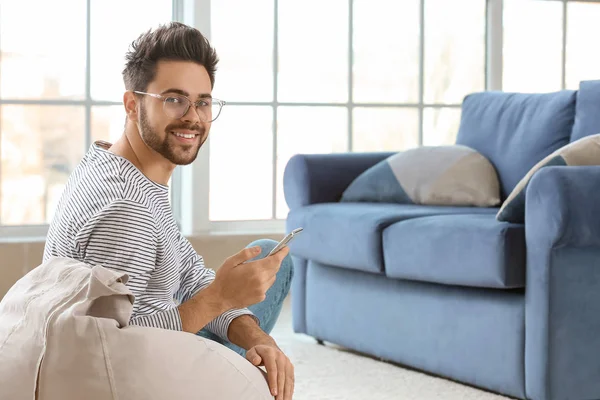 Happy young man with mobile phone at home — Stock Photo, Image