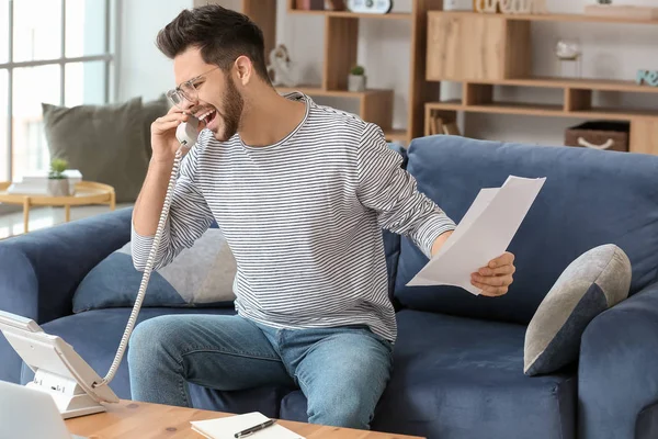 Screaming young man talking by telephone at home — Stock Photo, Image